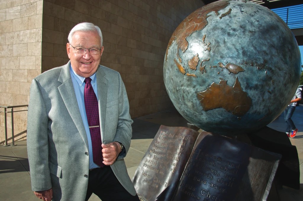 A man standing next to a statue of a globe