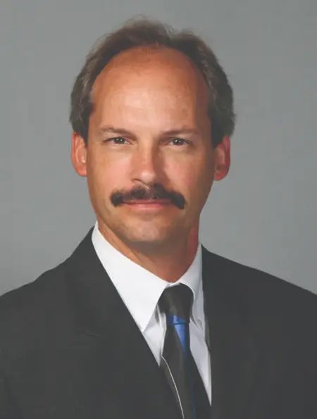 A man with a mustache wearing a suit and tie