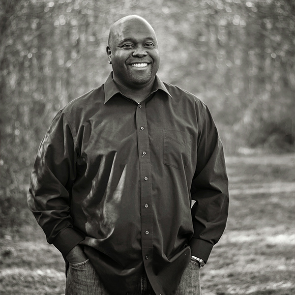 A man smiling with his hands in his pockets