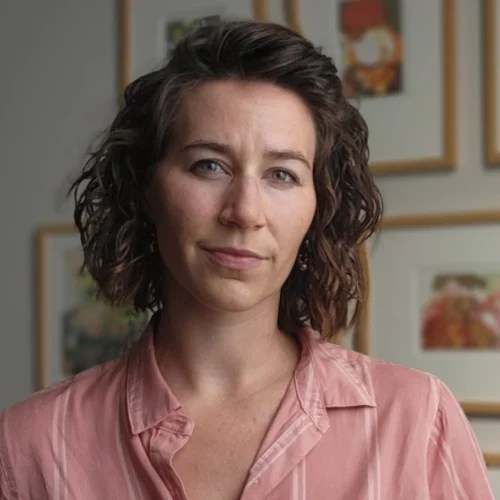 A woman with curly hair wearing a pink shirt