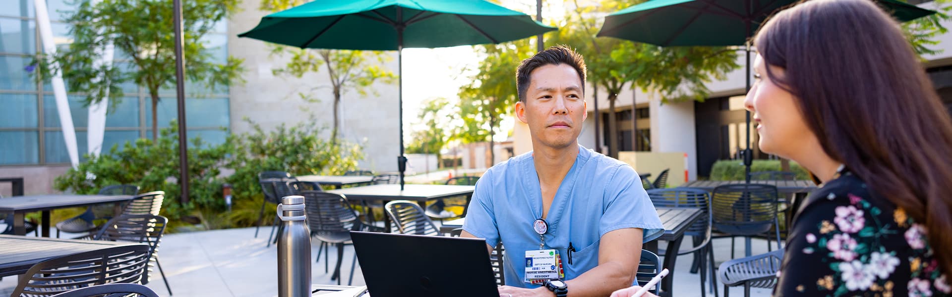 A man in a blue shirt sitting at a table with a laptop