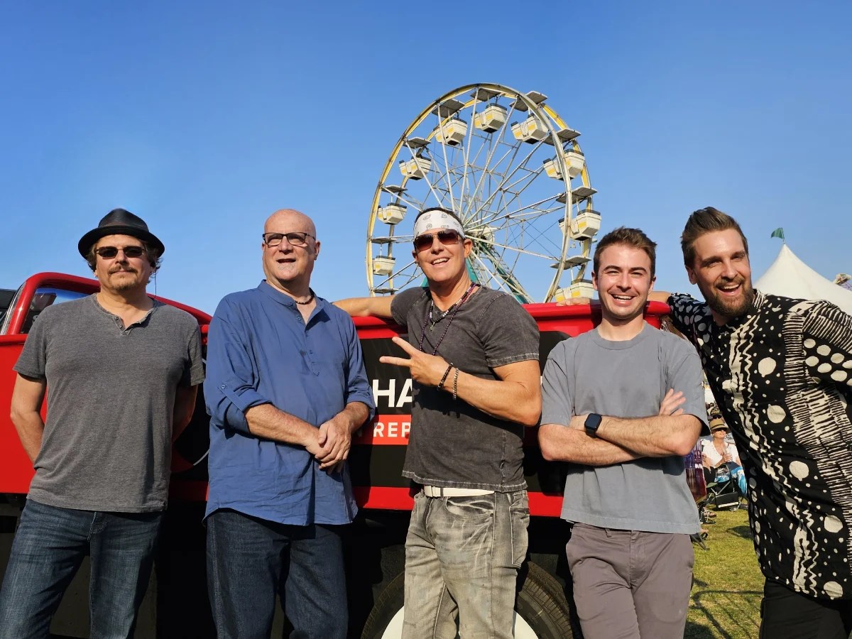 A group of men standing in front of a ferris wheel