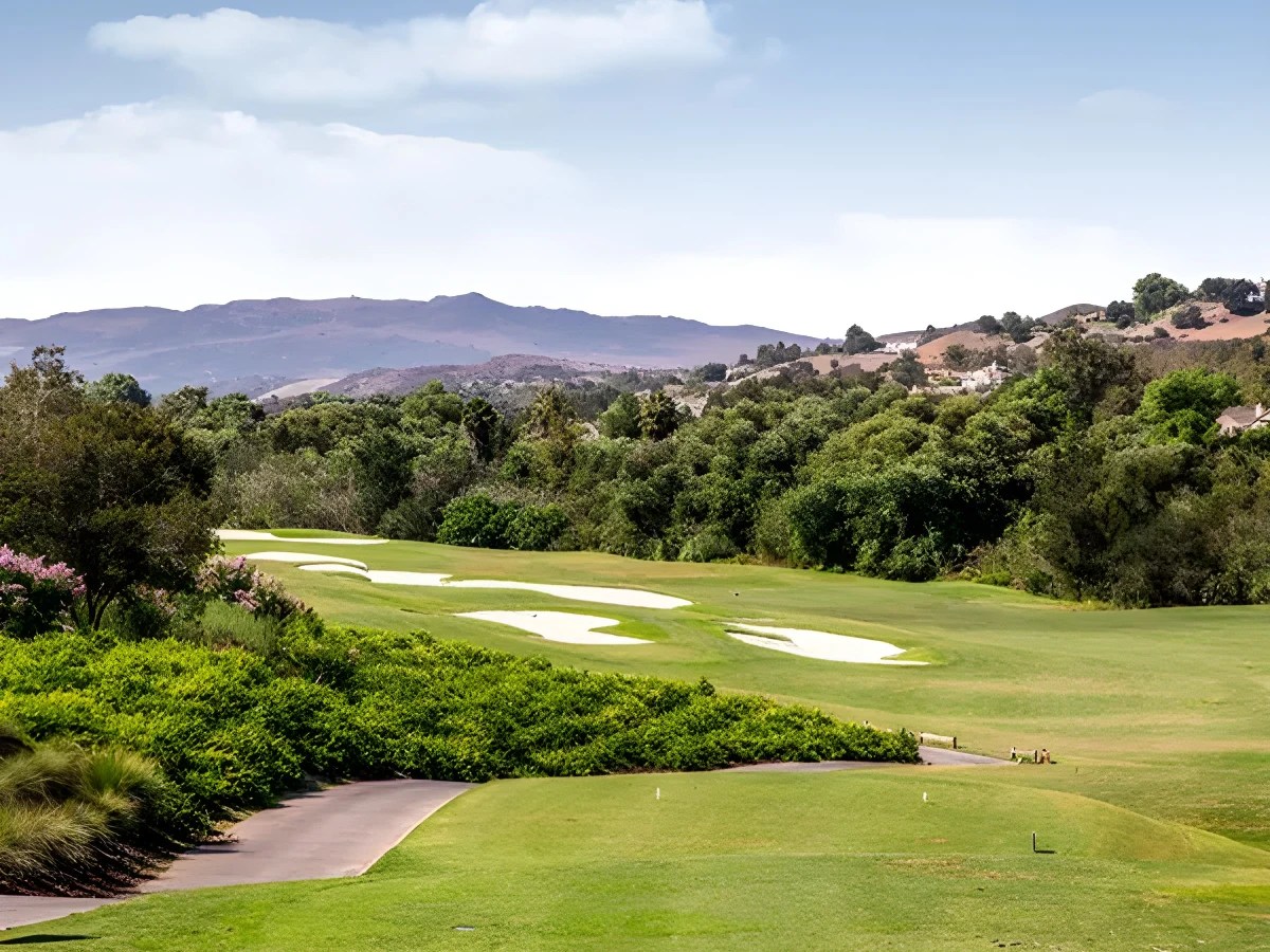 A golf course with trees and hills in the background