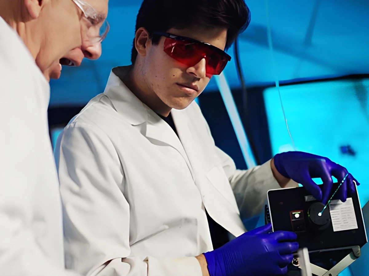 A man in white lab coat and gloves looking at a device