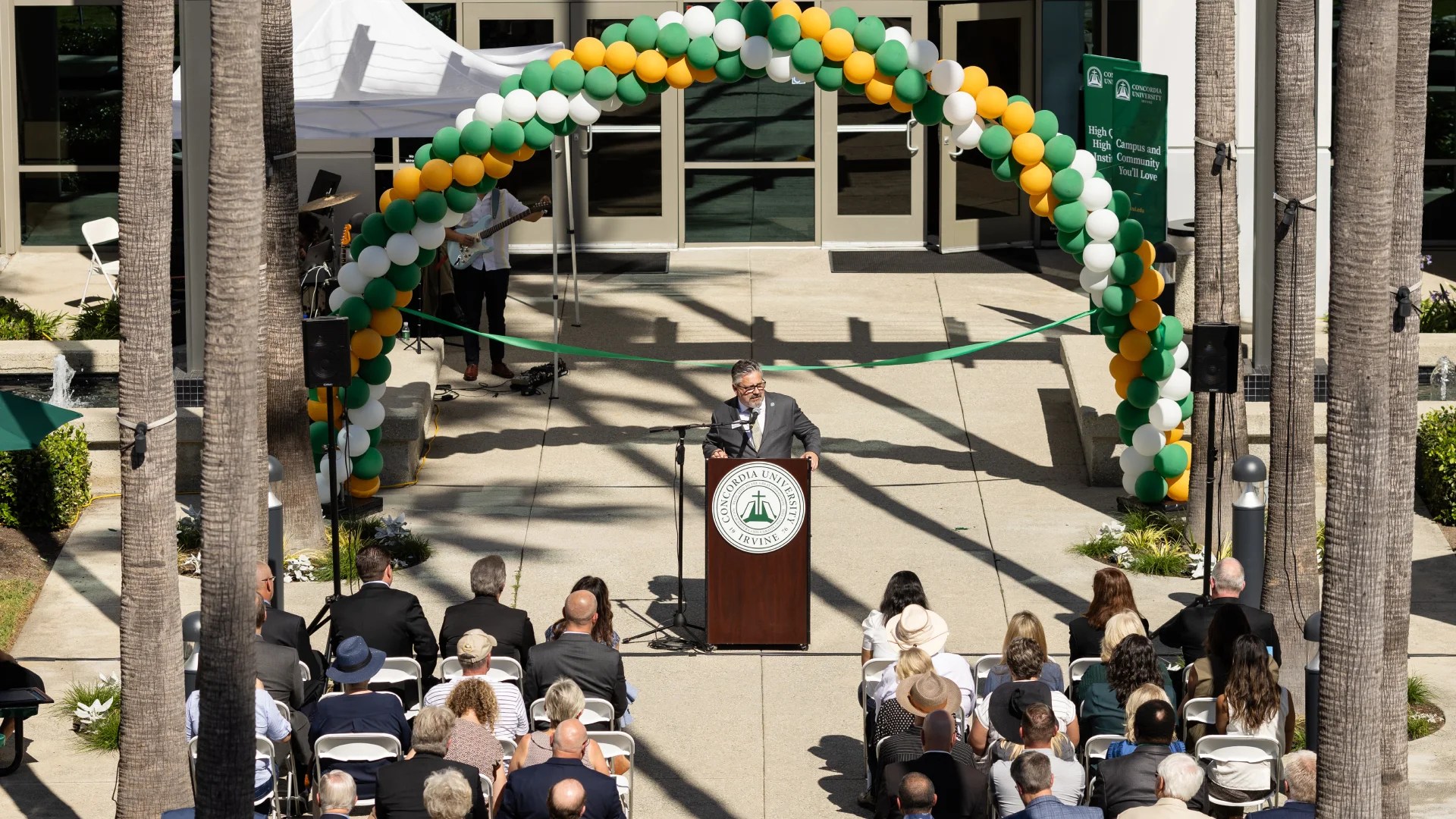 A man standing at a podium with a crowd of people sitting in chairs