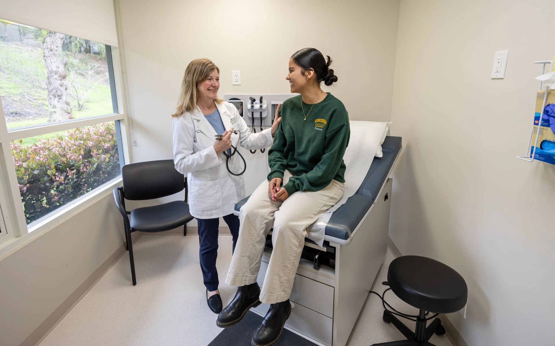 A woman in a white coat talking to a woman in a medical room
