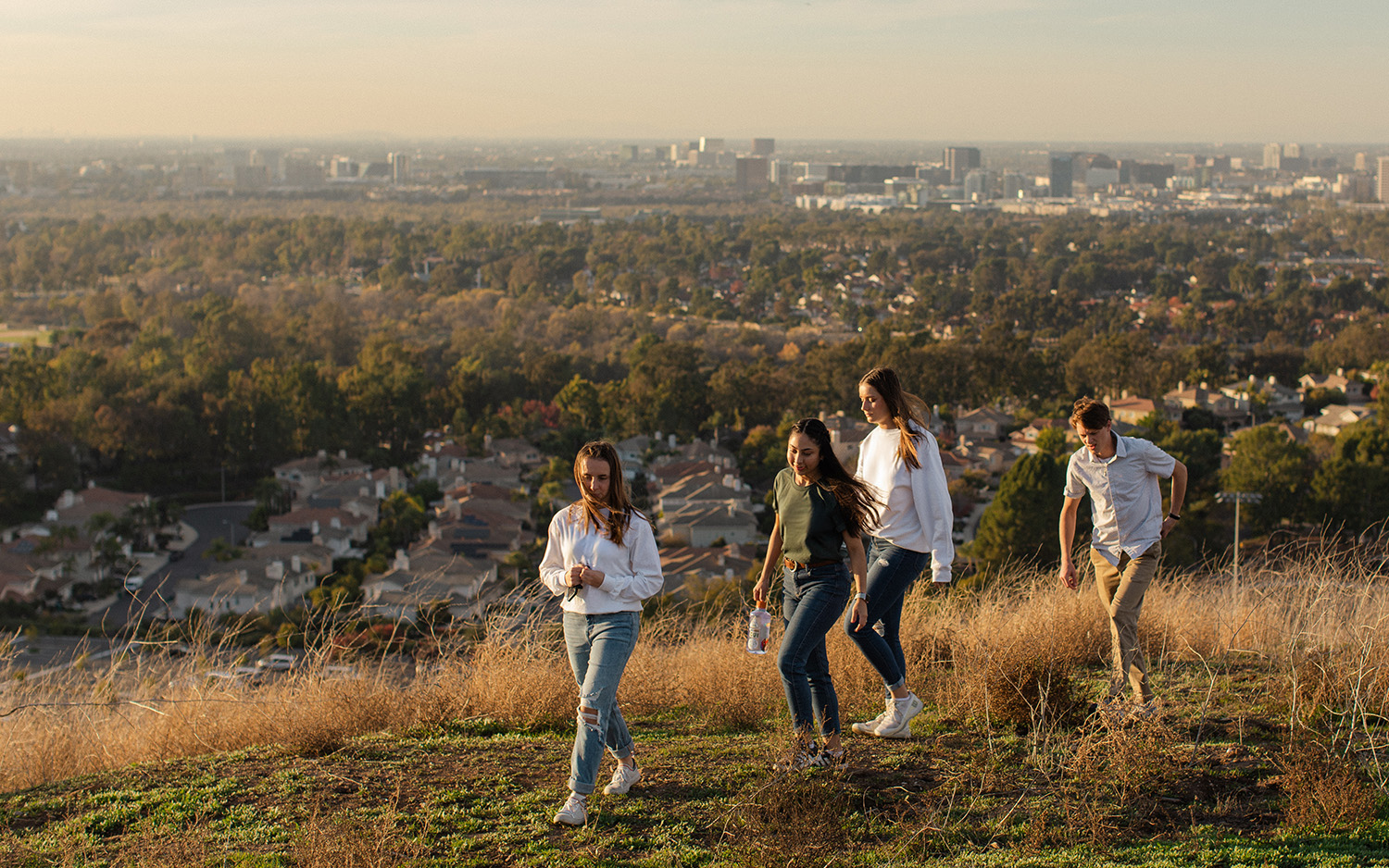 A group of people walking on a hill with a city in the background