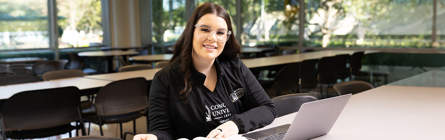 A woman sitting at a table with a laptop