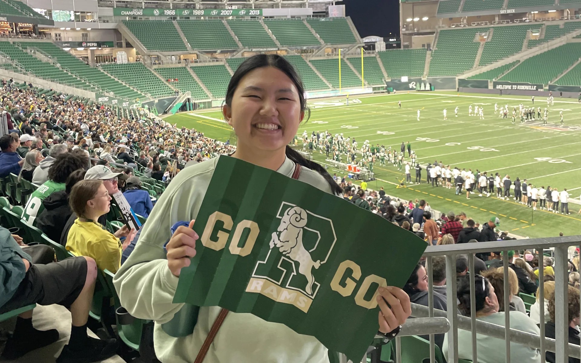 A woman holding a sign in front of a football stadium