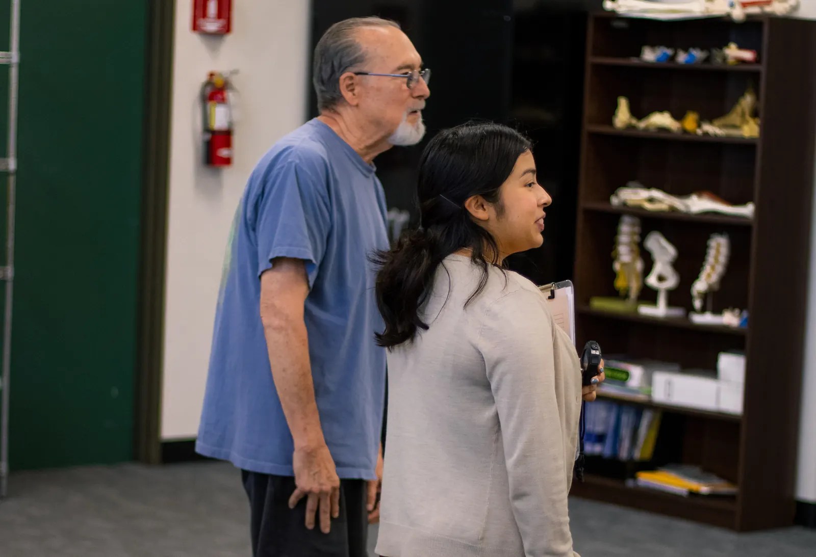 A student research assistant walks alongside a participant during a walking test in the lab.