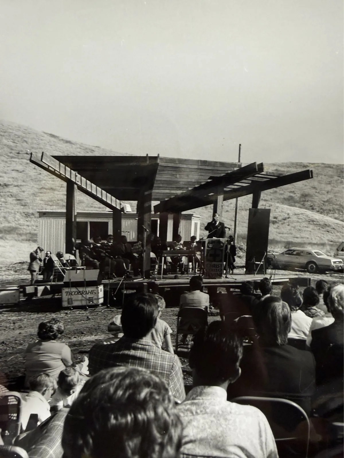 Early photo of a speaker at a podium on the Bird Sanctuary stage, facing a seated audience.