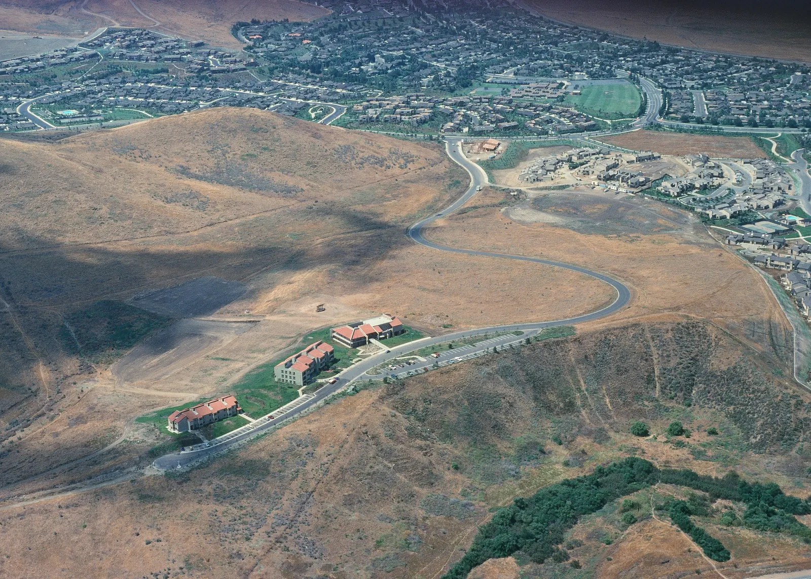 Aerial view of the early campus buildings on the Irvine hills, with neighborhoods in the distance.
