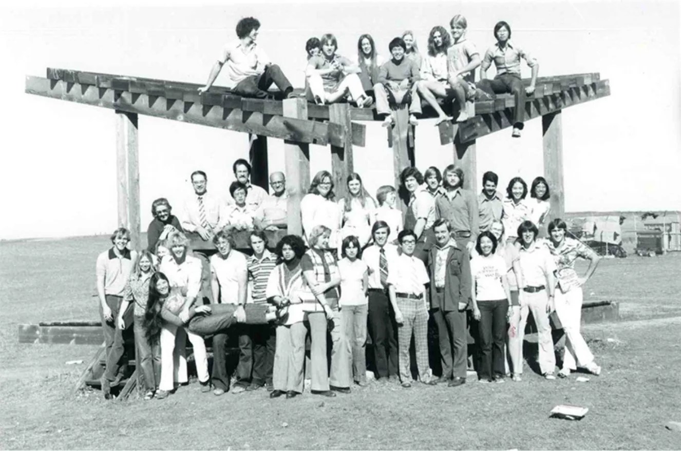 Black and white photo of a large group posing on top of and in front of the Bird Sanctuary.