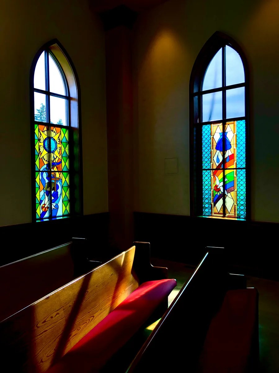 Stained glass windows above church pews