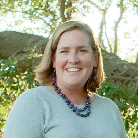 A woman smiling in front of trees
