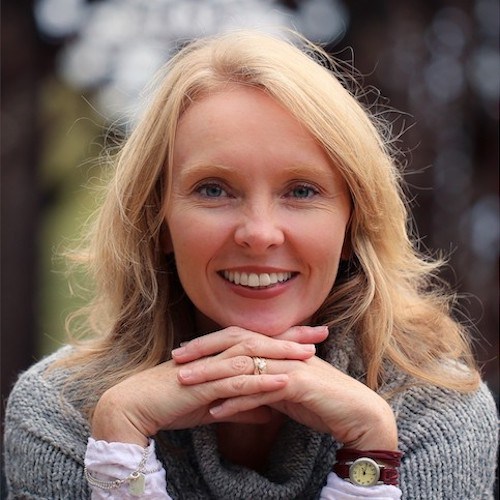 A woman smiling with her hands on her chin