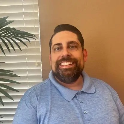 A man smiling in front of a plant