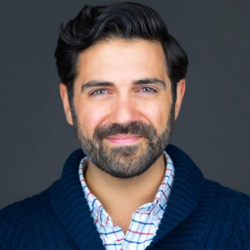 A man with a beard and mustache wearing a blue sweater